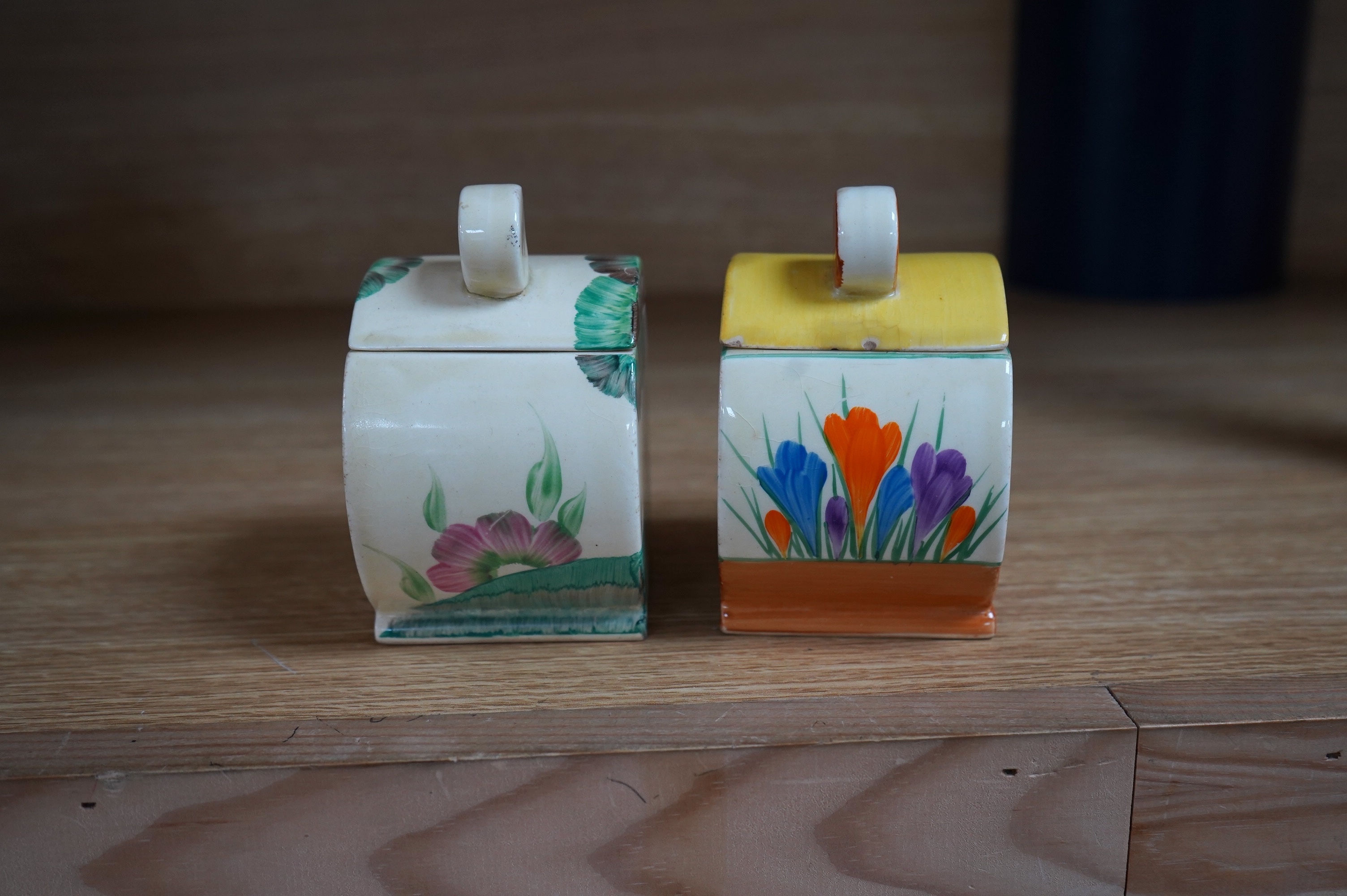 Two Clarice Cliff drum shaped preserve pots and covers, one in Crocus pattern and the other in Viscaria pattern. Condition - good